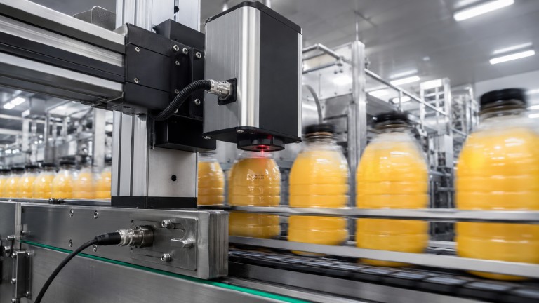 Industrial inline flying CO2 laser marking system integrated into high-speed packaging conveyor line, marking date codes on moving PET bottles